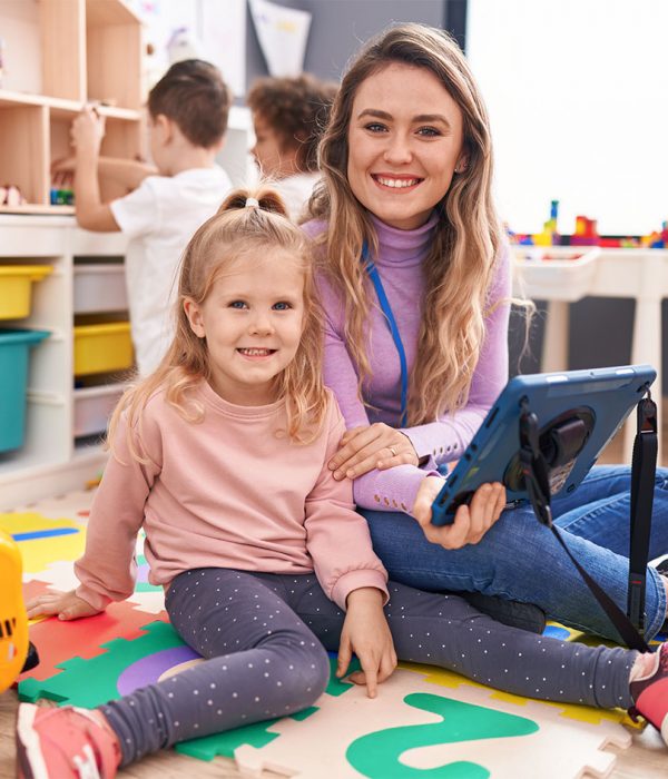 Woman and group of kids having lesson using touchpad at kindergarten